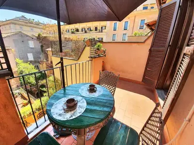 a balcony with a green table and chairs and an umbrella at Pantheon Penthouse in Rome