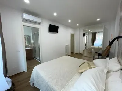 a white bedroom with a bed and a living room at SAINT PETER home and holiday apartment in Rome