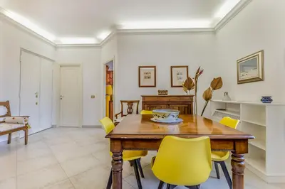 a living room with a table and yellow chairs at Emanuele House by GHOR in Rome