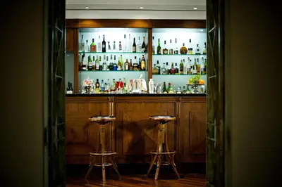 a bar with two stools in front of a shelf of alcohol at Hotel Ponte Sisto in Rome