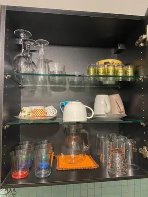 a shelf filled with glasses and a kettle and dishes at Garbatella, lovely mini apartment in Rome