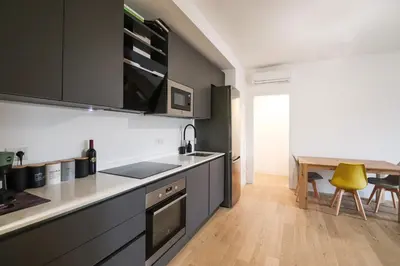 a kitchen with black cabinets and a table and a yellow chair at Modern Deluxe 2 Suites Apartment - 15min Colosseum & Metro 5min - AC, Wifi in Rome