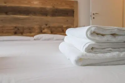 a stack of white towels sitting on a bed at Modern Deluxe 2 Suites Apartment - 15min Colosseum & Metro 5min - AC, Wifi in Rome
