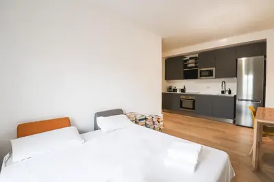 a bedroom with a white bed and a kitchen at Modern Deluxe 2 Suites Apartment - 15min Colosseum & Metro 5min - AC, Wifi in Rome