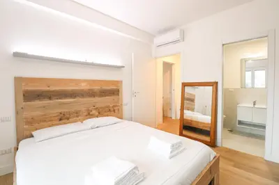 a white bedroom with a large bed and a mirror at Modern Deluxe 2 Suites Apartment - 15min Colosseum & Metro 5min - AC, Wifi in Rome