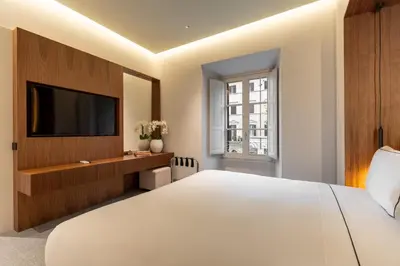 a bedroom with a large white bed and a flat screen tv at Domus Suites Colosseum in Rome
