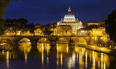 a bridge over a river with a building at night at The Artist's nest - Trastevere- Rome in Rome