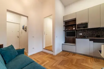 a living room with a couch and a kitchen at Bartolomeo de' Vaccinari - FromHometoRome in Rome