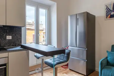 a kitchen with a table and a refrigerator at Bartolomeo de' Vaccinari - FromHometoRome in Rome