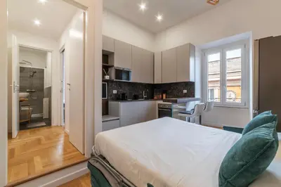 a bedroom with a large bed and a kitchen at Bartolomeo de' Vaccinari - FromHometoRome in Rome