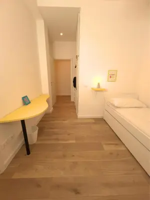 a room with a bed and a desk and a hallway at La mia casetta a Roma Montesacro in Rome