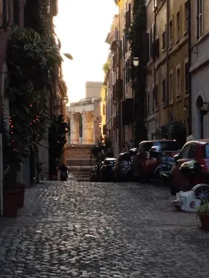 a cobblestone street in a city with cars parked at La casetta ai fori imperiali in Rome