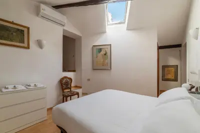 a white bedroom with a bed and a chair at Manara 29 - FromHometoRome in Rome