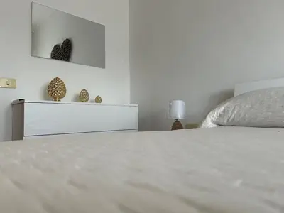 a white bedroom with a bed and a dresser at La Camilla in Rome