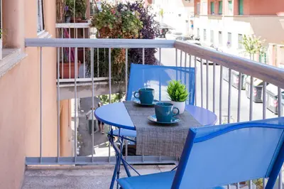 a table with two blue chairs and two cups on a balcony at Casa di Gina in Rome