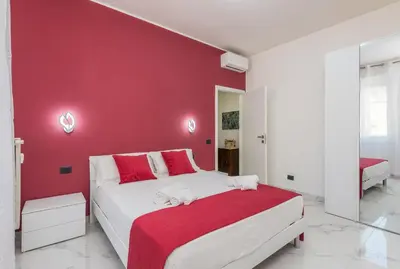 a bedroom with a red wall and a white bed at Casa di Gina in Rome