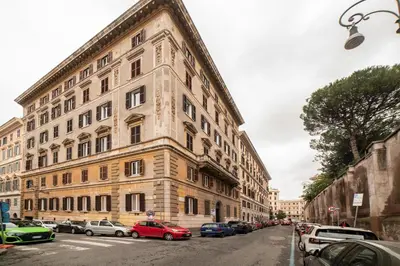 a large building on a city street with parked cars at Enjoy Colosseum Apartment in Rome