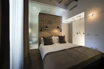 a bedroom with a large bed and a brick wall at Atypical Rooms in Rome