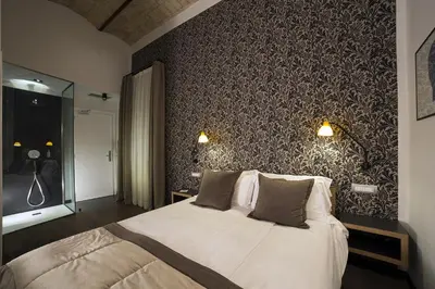 a bedroom with a bed and a wall covered in wallpaper at Atypical Rooms in Rome
