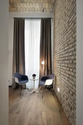a room with two chairs and a table and a brick wall at Atypical Rooms in Rome