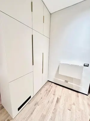 a white kitchen with white cabinets and a wooden floor at Luxury Nest Ponte Milvio in Rome