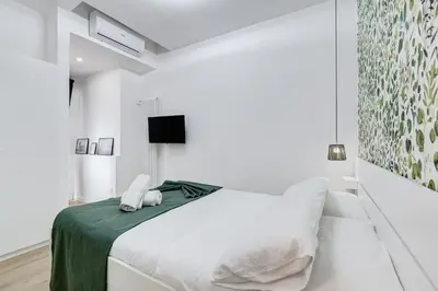 a white bedroom with a bed and a tv at New opening Ponte Milvio in Rome