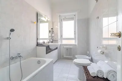 a white bathroom with a tub and a toilet and a sink at Roma 1950 - Bright apartment in octagonal tower in Rome