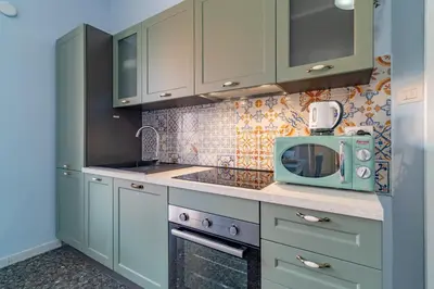 a kitchen with green cabinets and a microwave at Roma 1950 - Bright apartment in octagonal tower in Rome