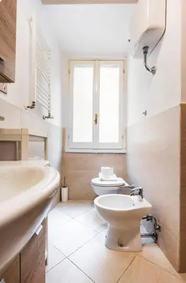 a bathroom with a toilet and a sink and a window at Piazza Farnese house in Rome
