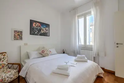 a white bedroom with two beds and a chair at TURATI GUEST HOUSe in Rome