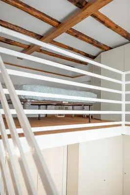 a bed in a room with white walls and wooden ceilings at Domus Palestro in Rome