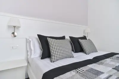 a white bed with black and white pillows on it at Lata Luxury Rooms in Rome