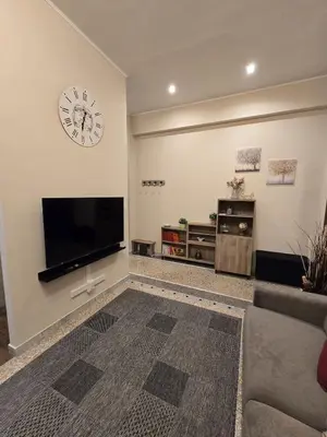 a living room with a large television and a clock on the wall at Ritiro Romano in Rome