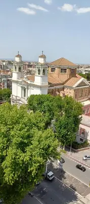 a white building with a clock tower in a city at Basilica santa Maria ausiliatrice in Rome
