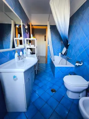 a blue tiled bathroom with a toilet and a sink at Basilica santa Maria ausiliatrice in Rome