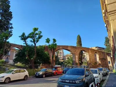 a bunch of cars parked on a street with an old bridge at Acquedotto di Nerone in Rome