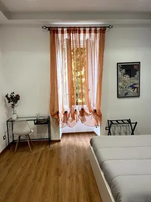 a bedroom with a bed and a desk and a window at MNC House Roma in Rome