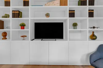 a living room with a tv on a white shelf at SANSO HOUSE - 2 bedrooms, 2 bathrooms, AC - for family in Rome
