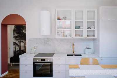 a white kitchen with white cabinets and a table at Modern apartment in Cornelia in Rome