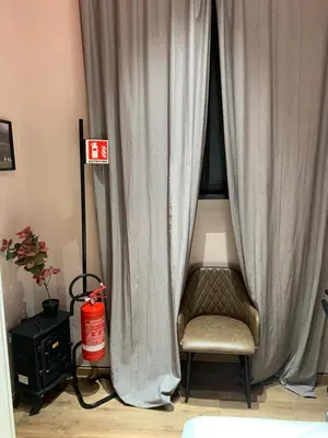 a room with a curtain and a chair and a fire extinguisher at eternal - vatican trionfale in Rome
