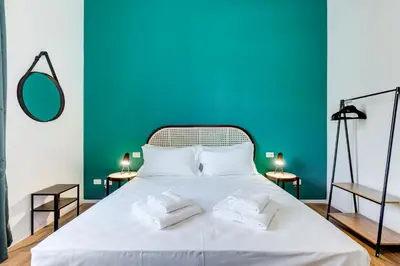 a bedroom with a white bed with a blue wall at BMGA l Aurelian 3Bdr 6-Guest Gem in Rome