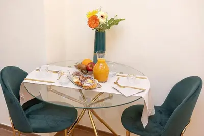 a glass table with a vase of flowers and a table with chairs at Dolcevita Vatican Apartment in Rome