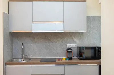 a kitchen with white cabinets and a sink and a microwave at Dolcevita Vatican Apartment in Rome