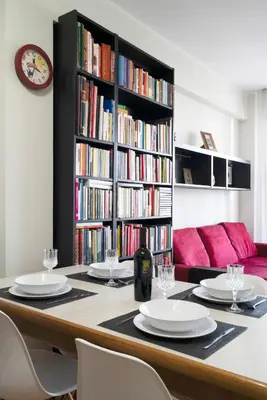 a table with chairs and a book shelf with books at Green park apartment in Rome