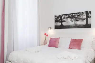 a bedroom with a white bed with pink pillows at asyouRhOME - Nico - San Pietro Vaticano in Rome