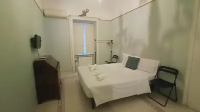 a bedroom with a white bed with a chair and a window at apt via cernaia rome center in Rome