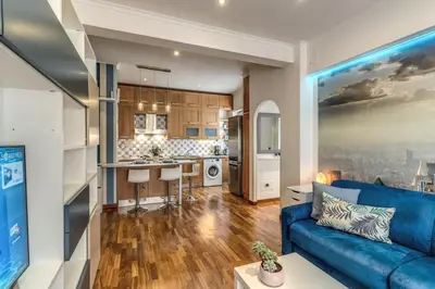 a living room with a blue couch and a kitchen at New York Apartment in Rome