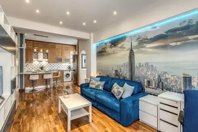 a living room with a blue couch and a kitchen at New York Apartment in Rome