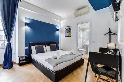 a bedroom with a large bed with a blue wall at VIVILO COLLECTION - Marche 54 Apart 4bdr - Close to Via Veneto in Rome