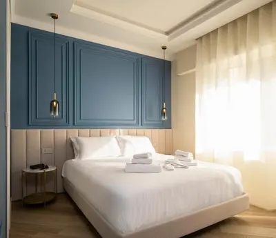 a bedroom with a large white bed with blue cabinets at Eudora Guesthouse Roma in Rome